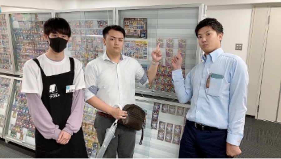 スーツ姿の女性が赤いバインダーを持ち、説明するような仕草をしている写真